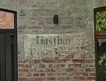 Alter Gasthof-Schriftzug im Backstein neben der Eingangstür
