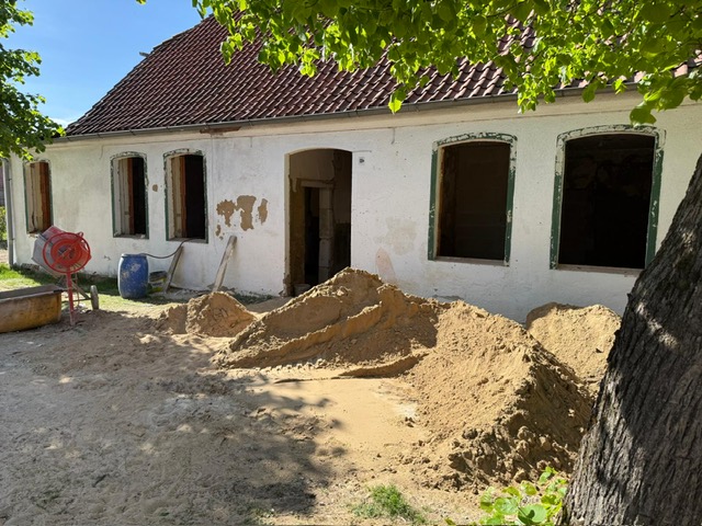 Baustelle im Mai 2025: Sandhaufen vor dem entkernten Gebäude mit weißer Fassade