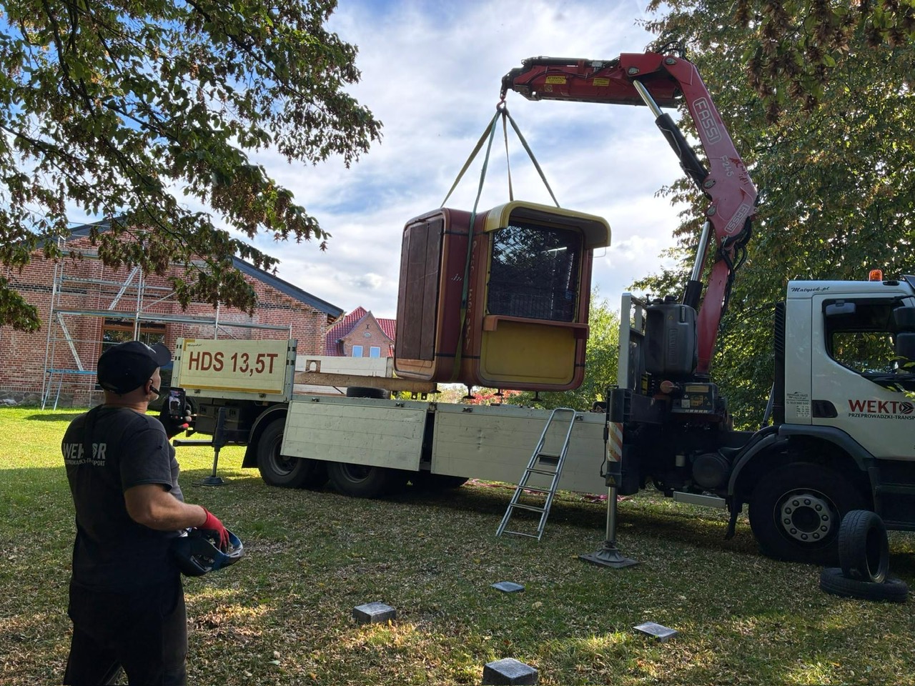 Ein Kiosk K67 hängt am Kran eines Lkw und wird auf der Wiese abgesetzt
